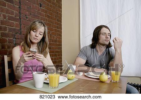 A young couple sitting at breakfast listening to MP3 players View Large Photo Image Stock Image - A young couple sitting at breakfast listening to MP3 players. Fotosearch