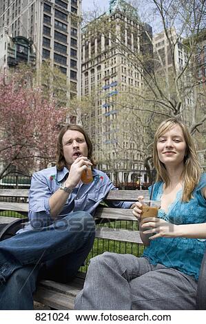 A young couple sitting on a park bench with iced coffees, Central Park, New York City View Large Photo Image Picture - A young couple sitting on a park bench with iced coffees, Central Park, New York City. Fotosearch