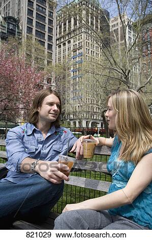 A young couple sitting on a park bench with iced coffees, Central Park, New York City View Large Photo Image Stock Photo - A young couple sitting on a park bench with iced coffees, Central Park, New York City. Fotosearch