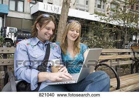 A young couple using a laptop on a park bench, Central Park, New York City View Large Photo Image Stock Image - A young couple using a laptop on a park bench, Central Park, New York City. Fotosearch