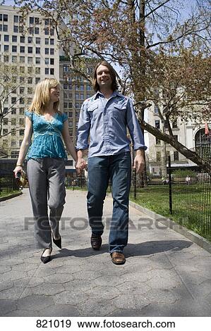 A young couple walking through a city park holding hands, Central Park, New York City View Large Photo Image Stock Photo - A young couple walking through a city park holding hands, Central Park, New York City. Fotosearch