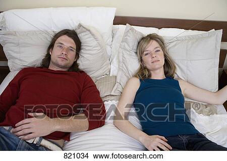 Picture - Portrait of a young couple lying down on a bed. Fotosearch