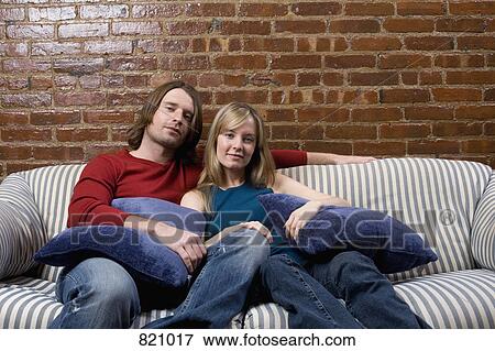 Stock Photo - Portrait of a young couple sitting on a sofa. Fotosearch