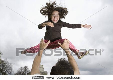 Stock Photo - A father throwing his daughter into the air. Fotosearch