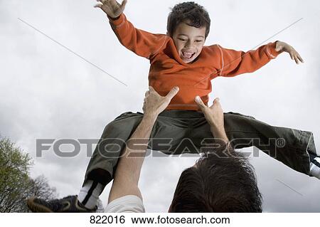 A father throwing his son into the air View Large Photo Image Stock Photograph - A father throwing his son into the air. Fotosearch