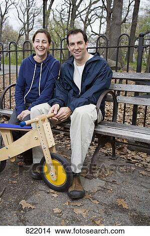 A man and woman sitting on a park bench together View Large Photo Image Picture - A man and woman sitting on a park bench together. Fotosearch
