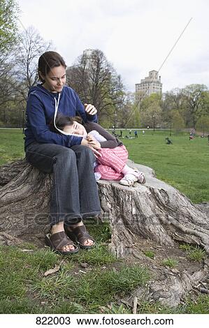 Stock Image - A mother and daughter sitting together on a tree stump. Fotosearch