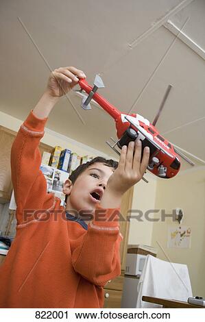 Stock Image - A young boy playing with a toy helicopter. Fotosearch