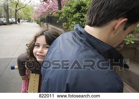A young girl on a wooden scooter peeking around her father View Large Photo Image Stock Image - A young girl on a wooden scooter peeking around her father. Fotosearch