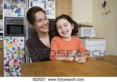 Portrait of a mother and daughter sitting at a kitchen table View Large Photo Image Stock Image - Portrait of a mother and daughter sitting at a kitchen table. Fotosearch
