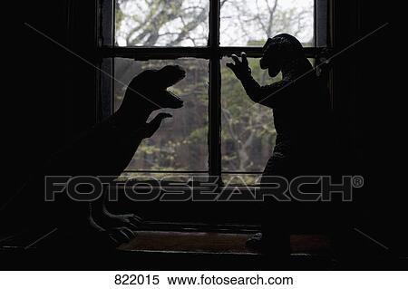 Stock Photography - Two dinosaur figurines in silhouette in front of a window . Fotosearch