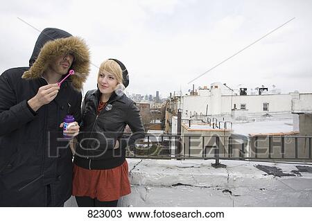 A young couple blowing bubbles on a rooftop View Large Photo Image Stock Image - A young couple blowing bubbles on a rooftop. Fotosearch