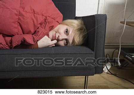 A young woman lying down on a sofa View Large Photo Image Stock Photography - A young woman lying down on a sofa. Fotosearch