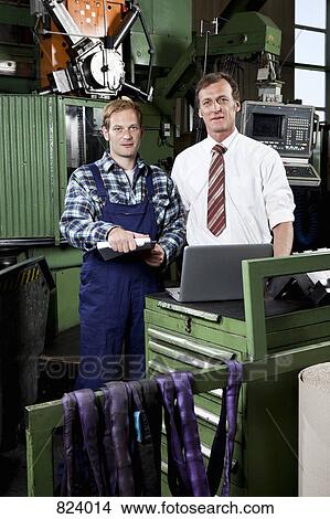 Picture - A factory manager and a factory worker in a metal parts factory. Fotosearch