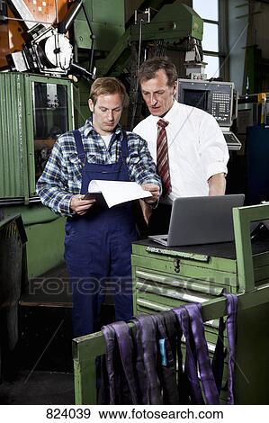 A factory manager and a factory worker in a metal parts factory View Large Photo Image Stock Photo - A factory manager and a factory worker in a metal parts factory. Fotosearch