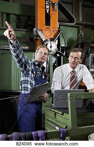 A factory manager and a factory worker in a metal parts factory View Large Photo Image Stock Photography - A factory manager and a factory worker in a metal parts factory. Fotosearch