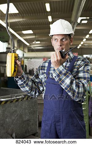 A factory worker using a walkie-talkie and operating a factory machine View Large Photo Image Stock Image - A factory worker using a walkie-talkie and operating a factory machine. Fotosearch
