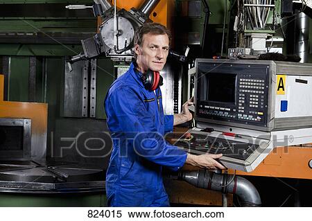 Stock Photography - A man operating a machine in a metal parts factory. Fotosearch