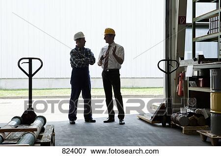 A manager talking to a manual worker in a warehouse doorway, back lit View Large Photo Image Stock Photo - A manager talking to a manual worker in a warehouse doorway, back lit. Fotosearch