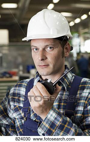 Stock Image - Portrait of a factory worker holding a walkie-talkie. Fotosearch