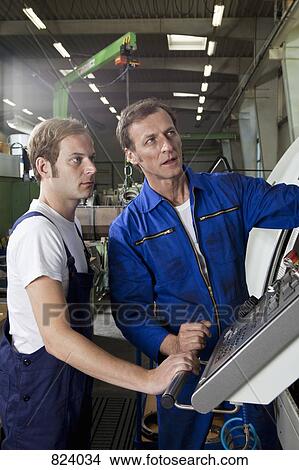 Two manual workers talking and working in a factory View Large Photo Image Picture - Two manual workers talking and working in a factory. Fotosearch
