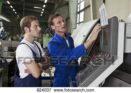Two manual workers talking and working in a factory View Large Photo Image Stock Photo - Two manual workers talking and working in a factory. Fotosearch