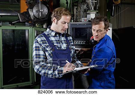 Two men in a metal parts factory reviewing a clipboard View Large Photo Image Stock Photograph - Two men in a metal parts factory reviewing a clipboard. Fotosearch