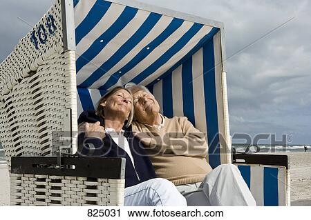 A senior couple sitting together in a hooded beach chair View Large Photo Image Stock Image - A senior couple sitting together in a hooded beach chair. Fotosearch