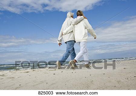 Stock Image - A senior couple walking on a beach. Fotosearch