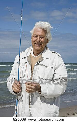 Stock Photo - A senior man holding a fishing rod. Fotosearch
