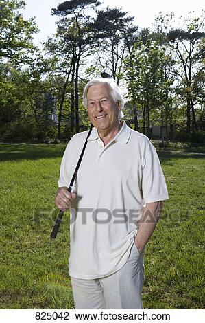 A senior man holding a golf club View Large Photo Image Stock Image - A senior man holding a golf club. Fotosearch