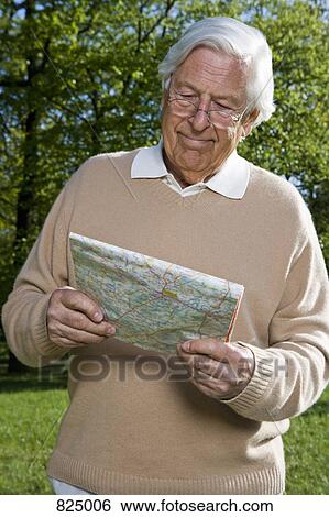Stock Photograph - A senior man looking at a map, outdoors. Fotosearch