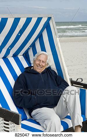 Stock Photo - A senior man sitting on a hooded beach chair. Fotosearch