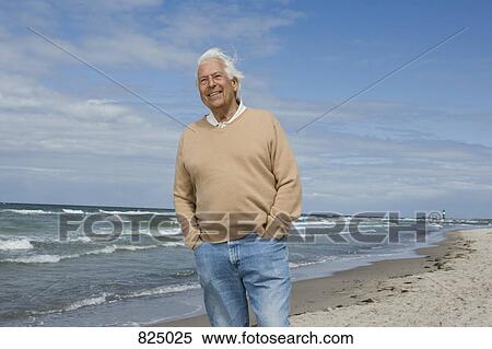 Stock Photography - A senior man standing on a beach. Fotosearch