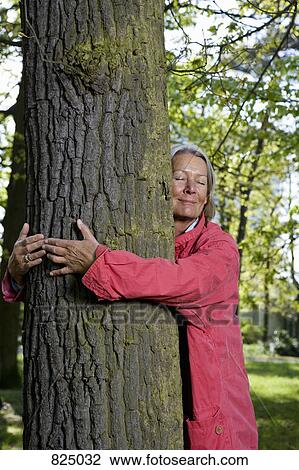 Stock Image - A senior woman hugging a tree. Fotosearch