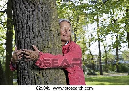 A senior woman hugging a tree View Large Photo Image Stock Photography - A senior woman hugging a tree. Fotosearch