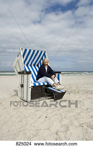 A senior woman sitting in a hooded beach chair View Large Photo Image Picture - A senior woman sitting in a hooded beach chair. Fotosearch