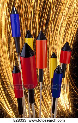 Stock Image - Rocket firecrackers with a firework display behind them. Fotosearch