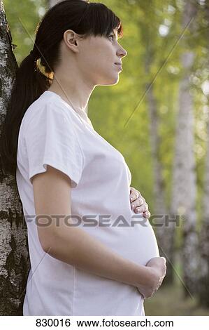 A pregnant woman holding her stomach, outdoors View Large Photo Image Stock Photograph - A pregnant woman holding her stomach, outdoors. Fotosearch