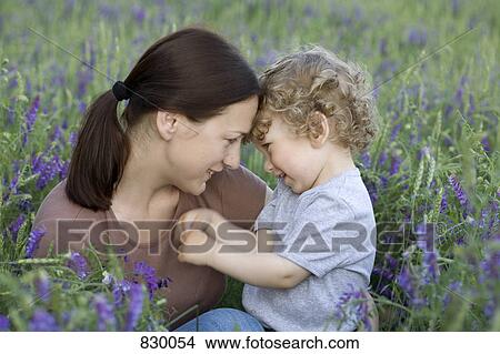 A woman and a young boy sitting face to face in a field View Large Photo Image Picture - A woman and a young boy sitting face to face in a field. Fotosearch