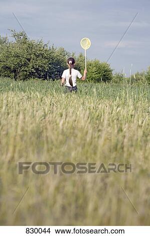 Picture - Rear view of a young girl catching butterflies in a field. Fotosearch