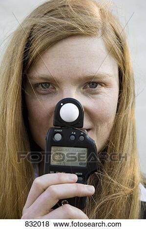 A woman holding a light meter in front of her face View Large Photo Image Stock Photo - A woman holding a light meter in front of her face. Fotosearch