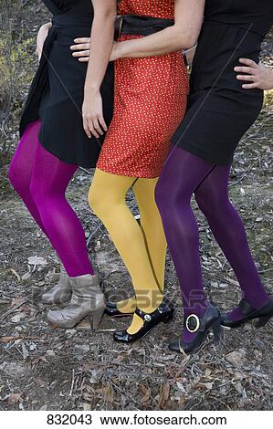 Stock Image - Waist down view of three women dressed in party clothes. Fotosearch