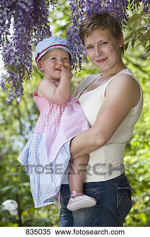 A formal portrait of a mother and her baby girl standing under a wisteria View Large Photo Image Stock Photography - A formal portrait of a mother and her baby girl standing under a wisteria. Fotosearch