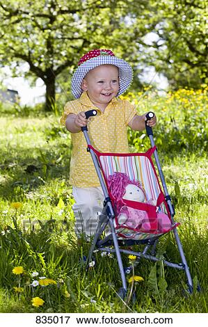 A toddler pushing her doll in a baby stroller View Large Photo Image Stock Photo - A toddler pushing her doll in a baby stroller. Fotosearch