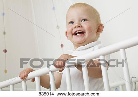 Picture - A toddler standing in a baby crib. Fotosearch