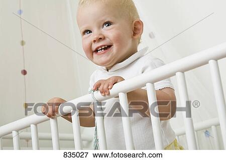 A toddler standing in a baby crib View Large Photo Image Stock Photo - A toddler standing in a baby crib. Fotosearch