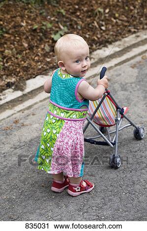 A toddler with a baby stroller View Large Photo Image Stock Image - A toddler with a baby stroller. Fotosearch