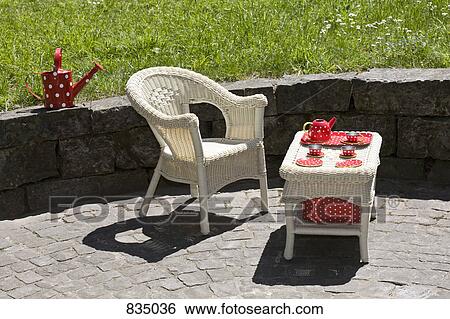 A wicker chair and table with a child's tea set, outdoors View Large Photo Image Stock Photograph - A wicker chair and table with a child's tea set, outdoors. Fotosearch