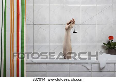 A human hand sticking out of a bathtub holding a bath plug View Large Photo Image Picture - A human hand sticking out of a bathtub holding a bath plug. Fotosearch